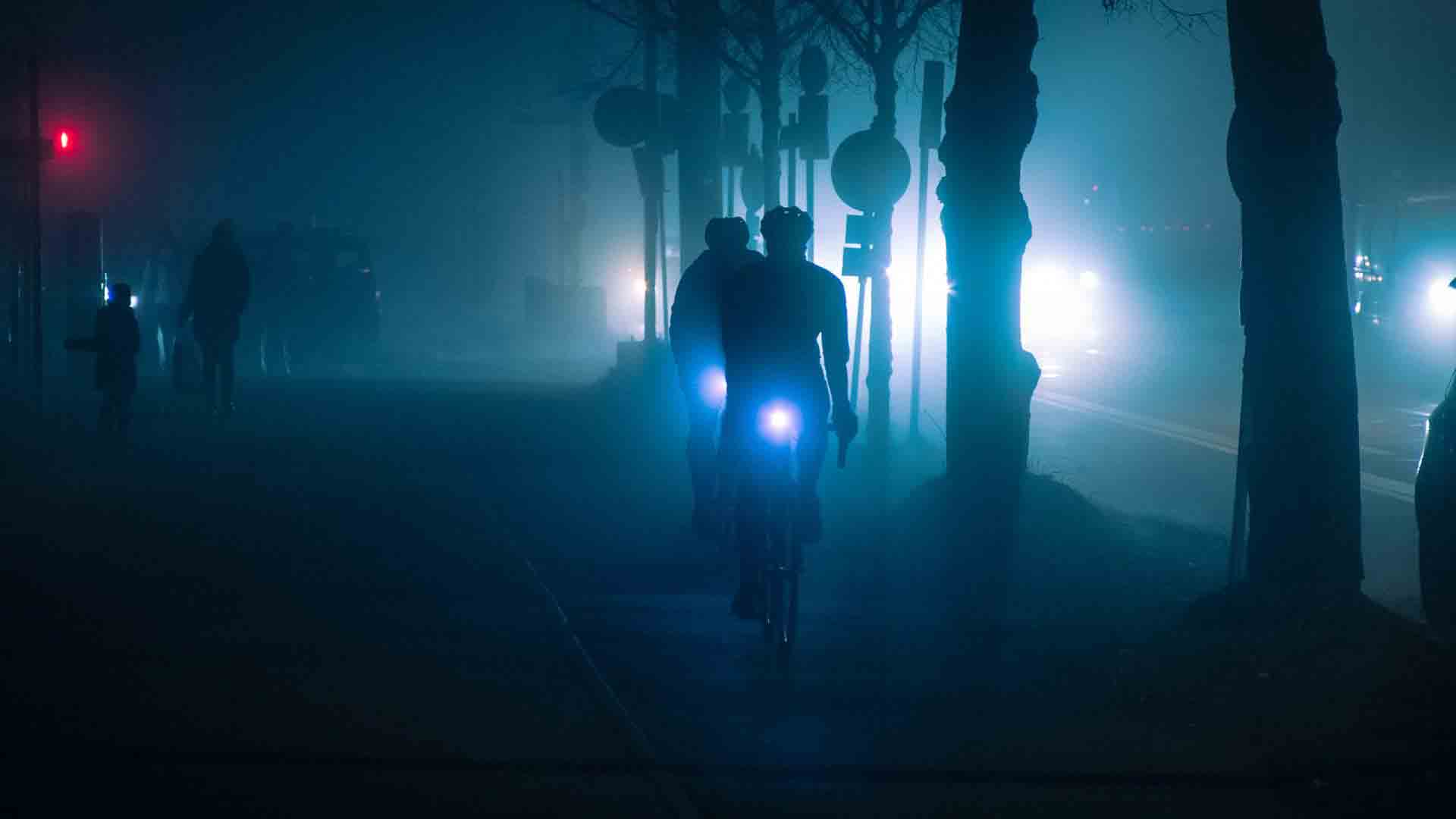 Zdjęcie kolarzy jadących w nocy z oświetleniem
